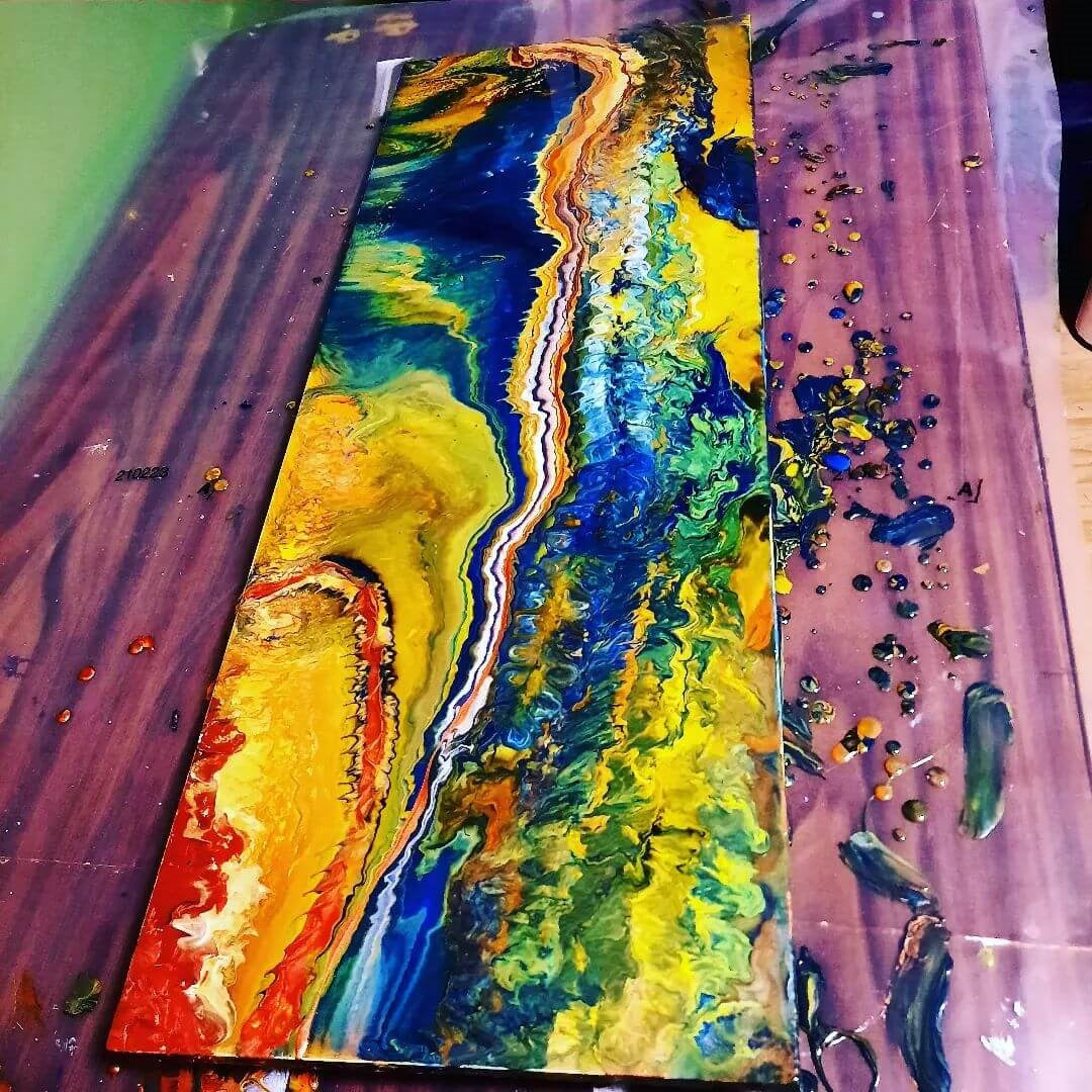 A colourful coffee table with rainbow acrylic pour paint over the top.