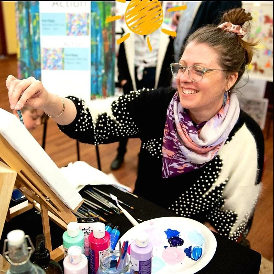 13. Artist Kate Biggs painting a white canvas on a wooden easel with Mont Marte paints next to the easel.