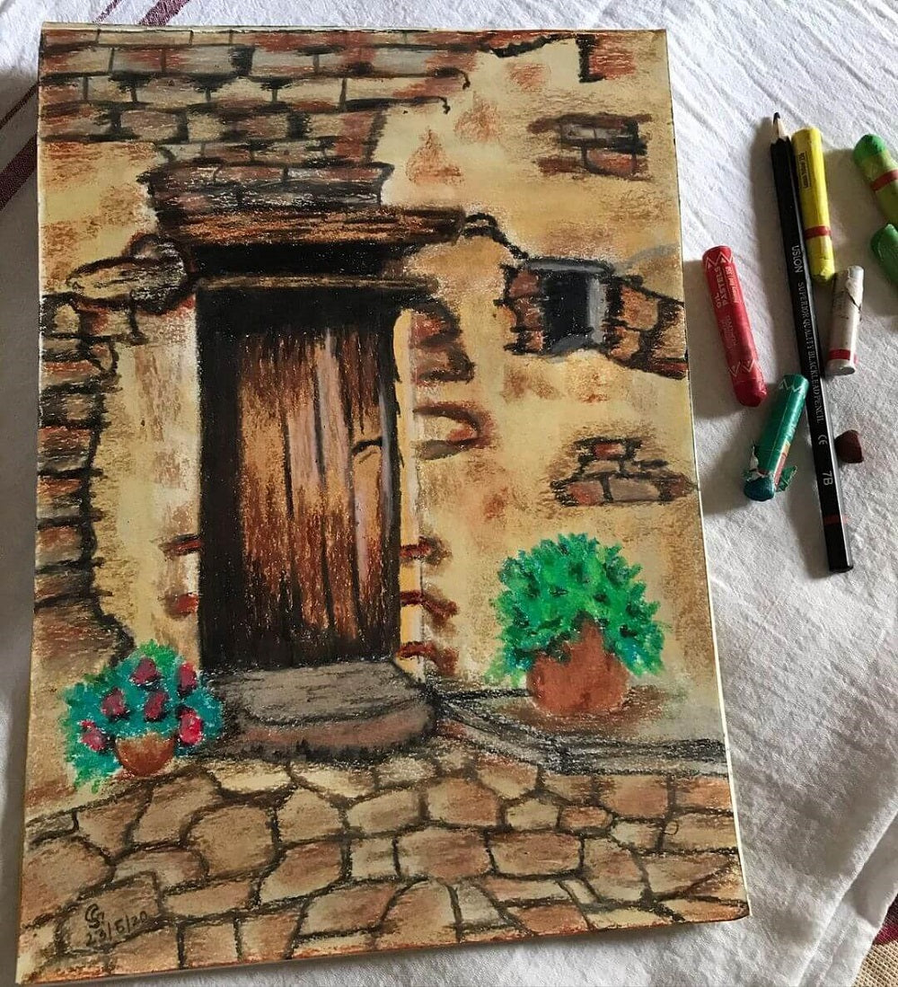 Oil pastel drawing of an old door with two oil pastels next to the artwork.