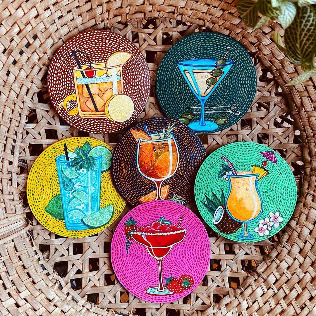 14. Six mulit coloured coasters with various cocktails painted on top.