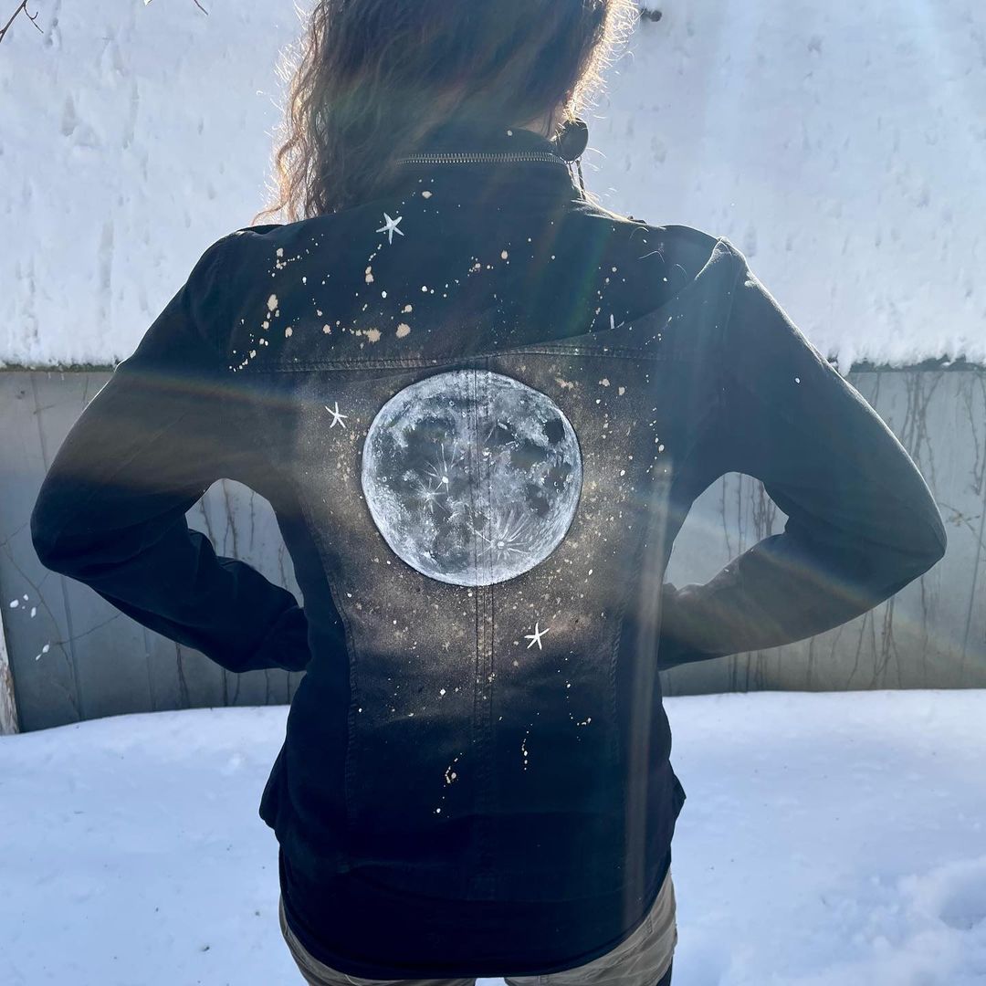 Full moon painted on the back of a dark black denim jackets.