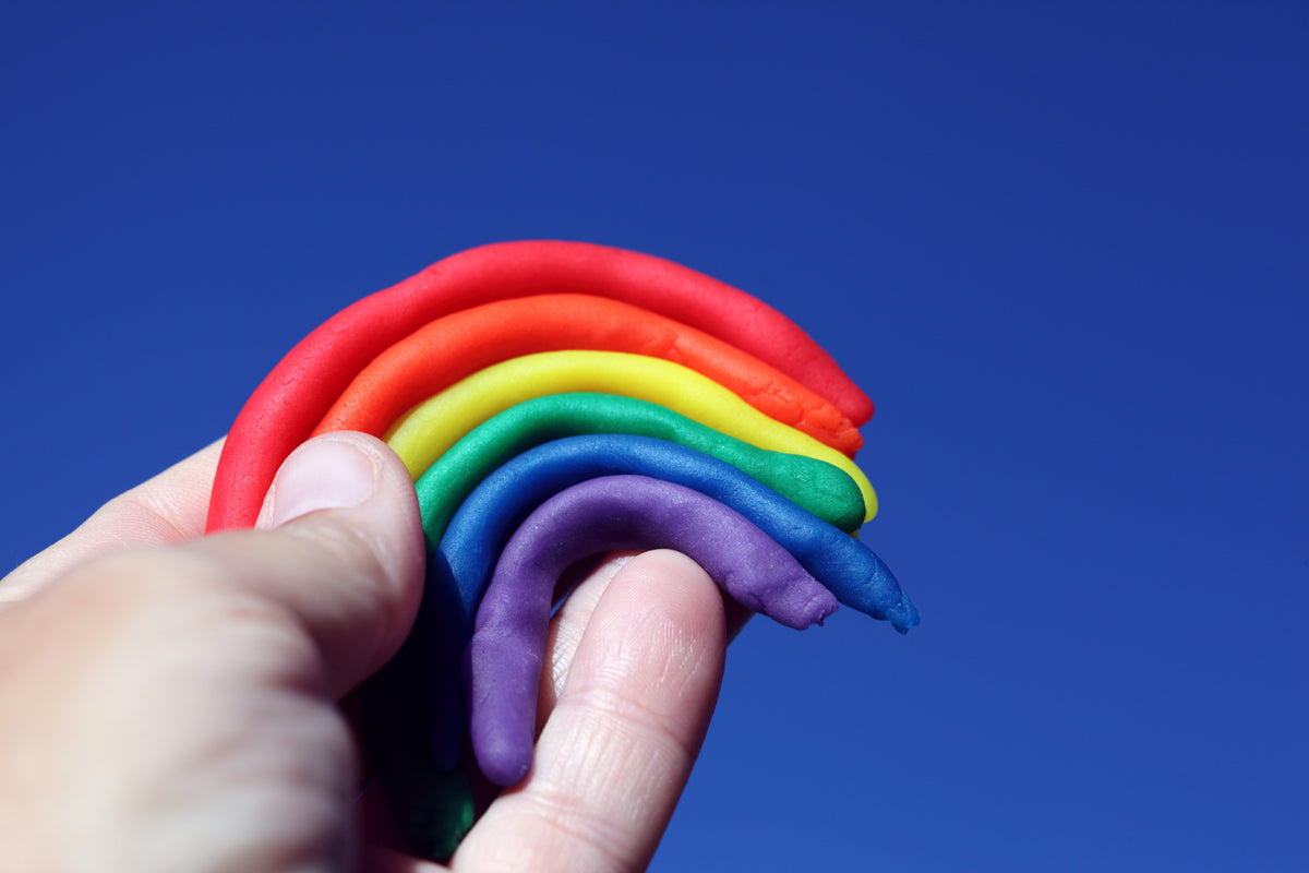 Hand holding a rainbow polymer clay sculpture.