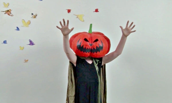 Child wearing a pumpkin on their head for Halloween.