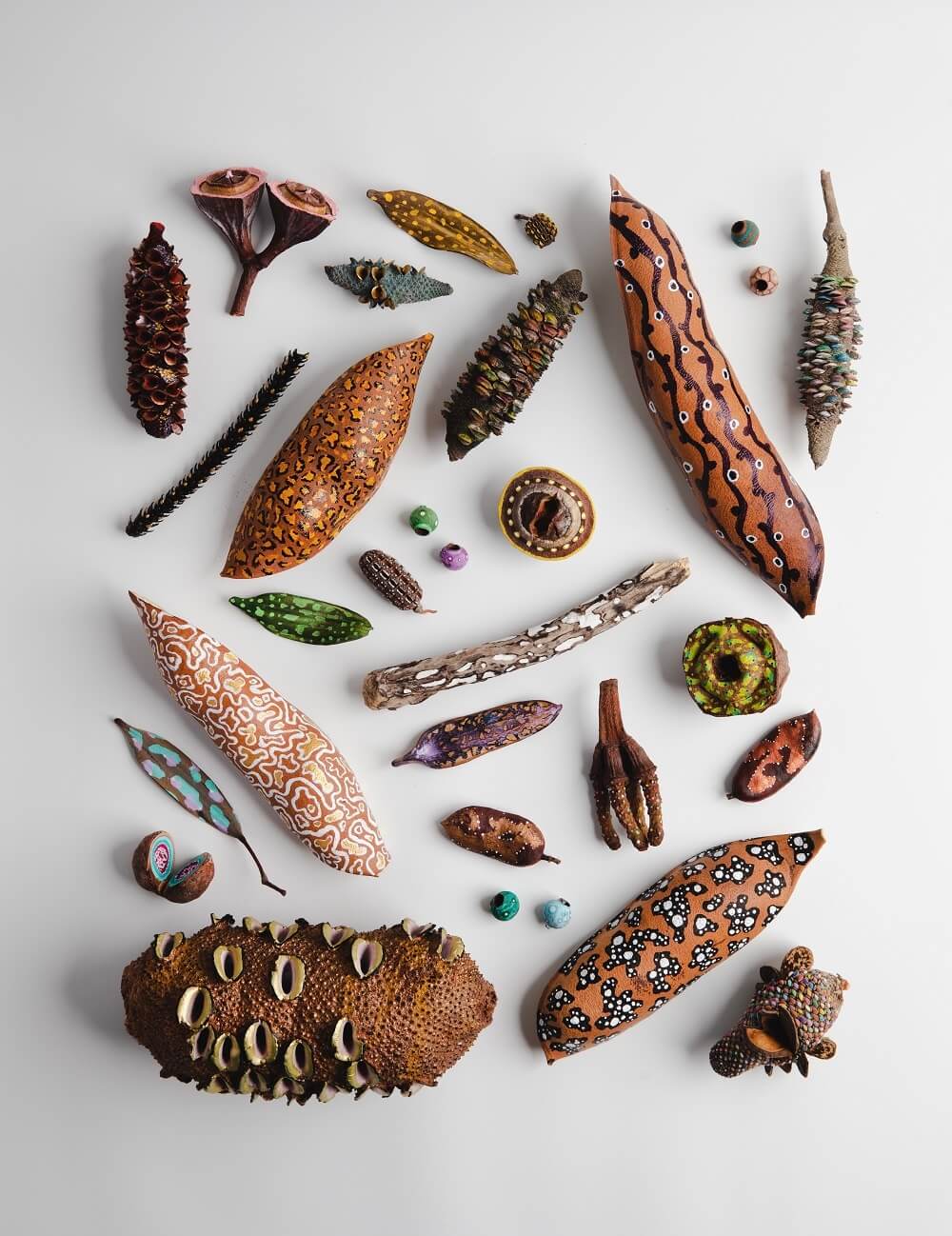 Delicately painted seedpods, leaves and pinecones in a flat lay