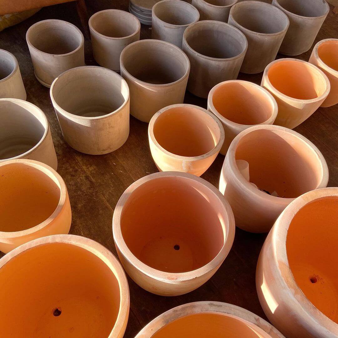 A large number of terracotta pots both orange and white sitting side by side together.