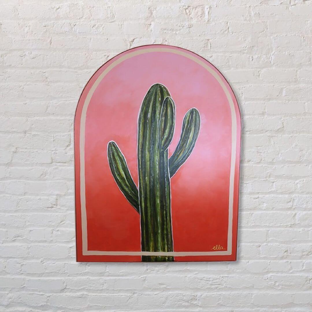 2. A painted cactus artwork on a white brick wall.