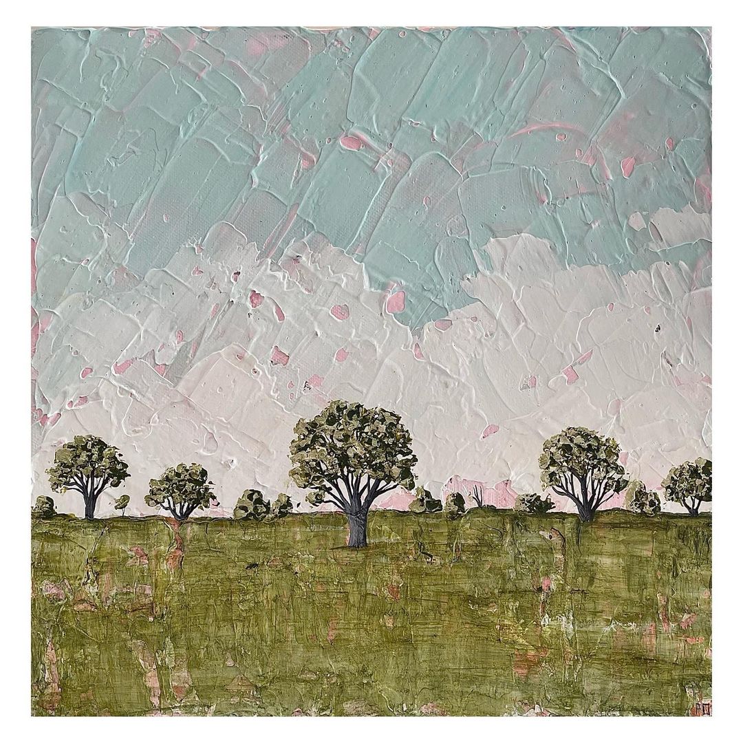 A textured rural landscape with blue, white and pink layered sky and small trees.