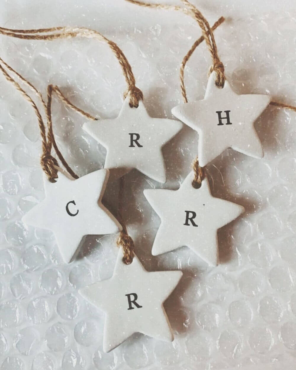 Clay star Christmas decorations with letters of the alphabet on each one.