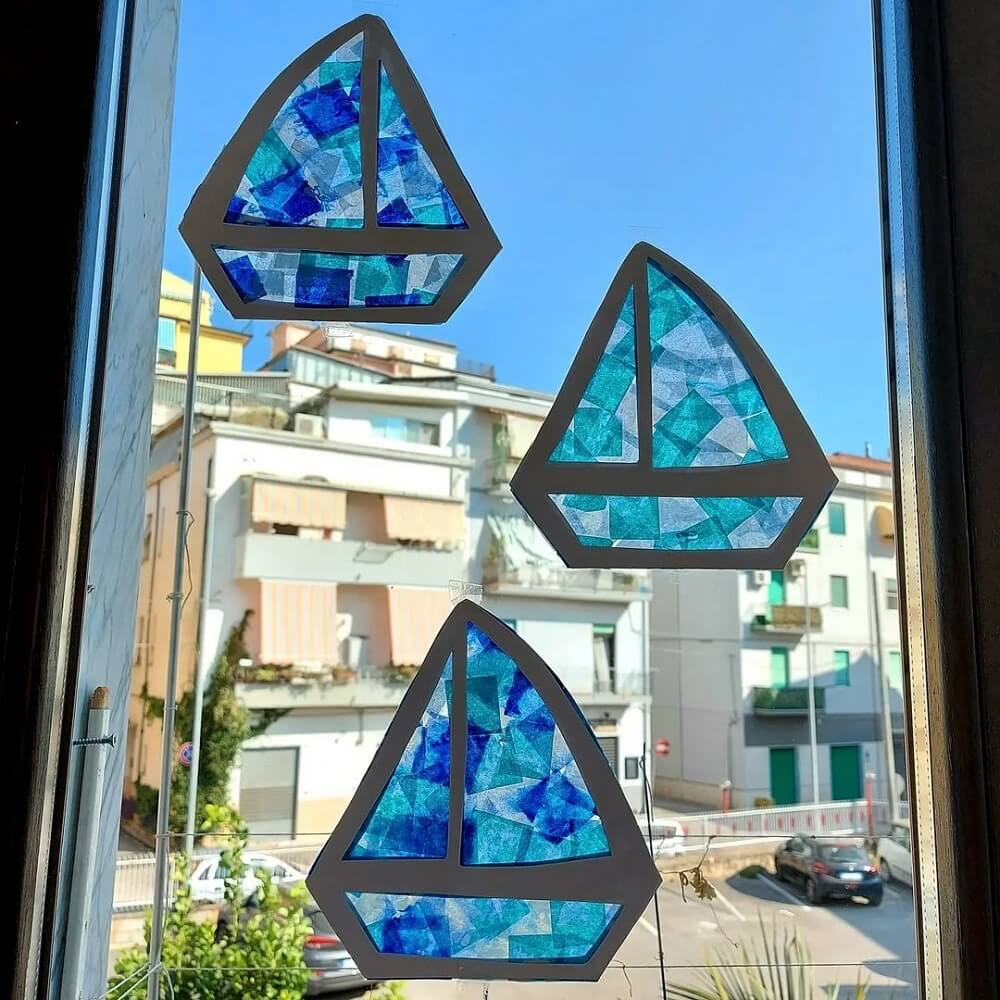 Three sailboats on a window made from cardboard with cellophane window.