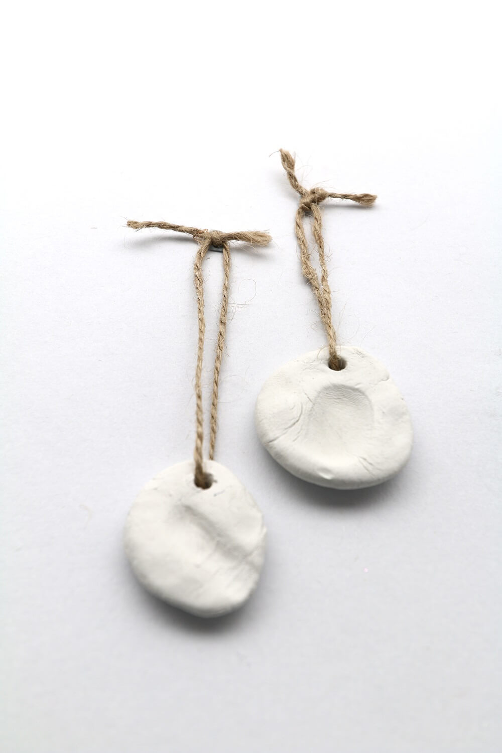Two clay medallions with fingerprints and a thread of kitchen twine.