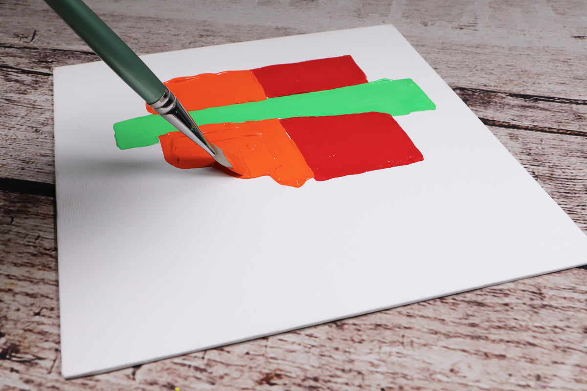Brush painting orange square next to red square and green rectangle.