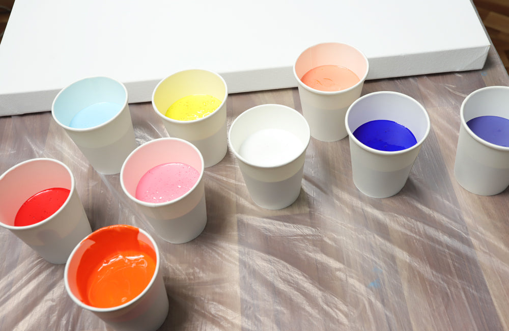 Cups of different coloured pouring paint