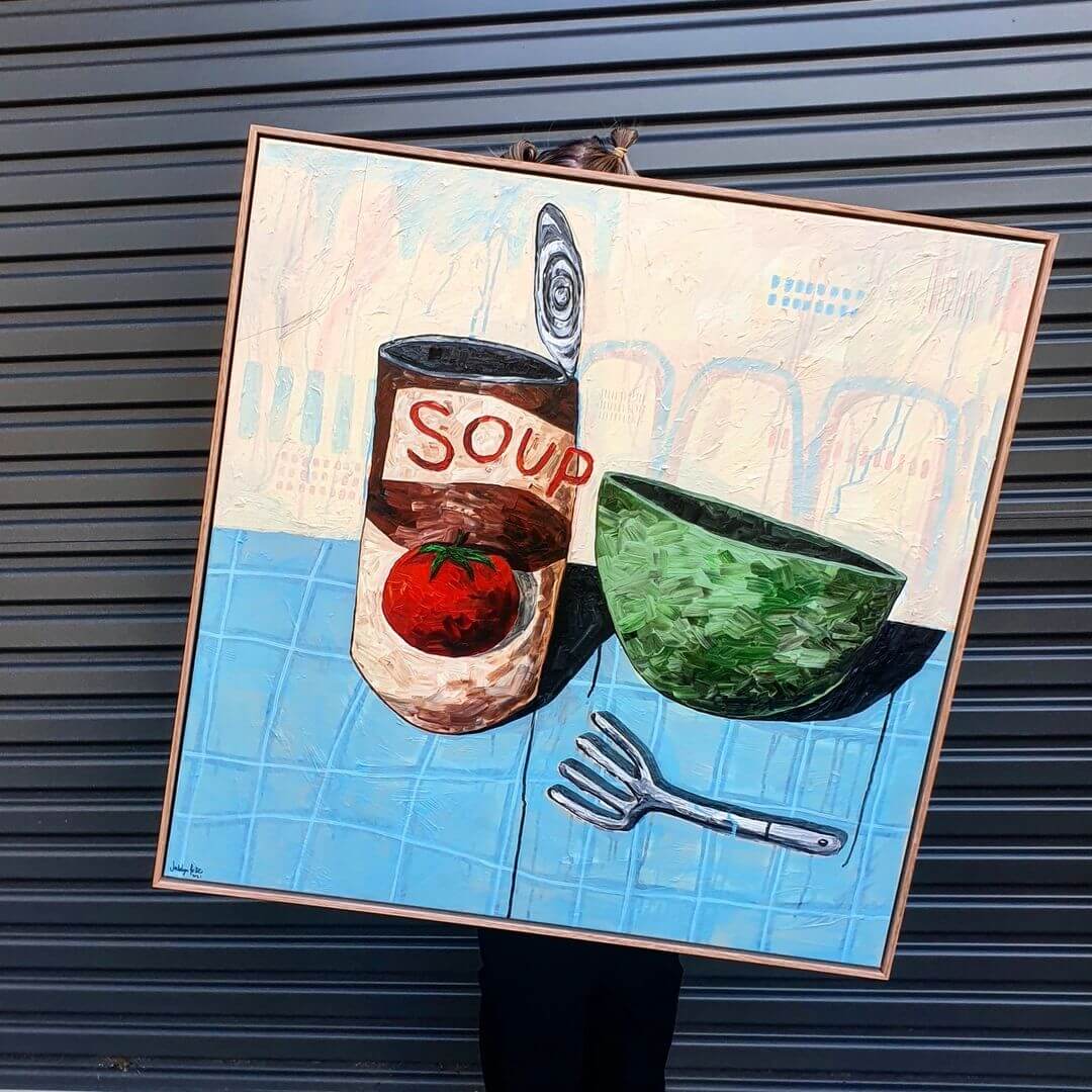 Abstract painting on canvas of a soup can, a green bowl and fork laying on a bench.