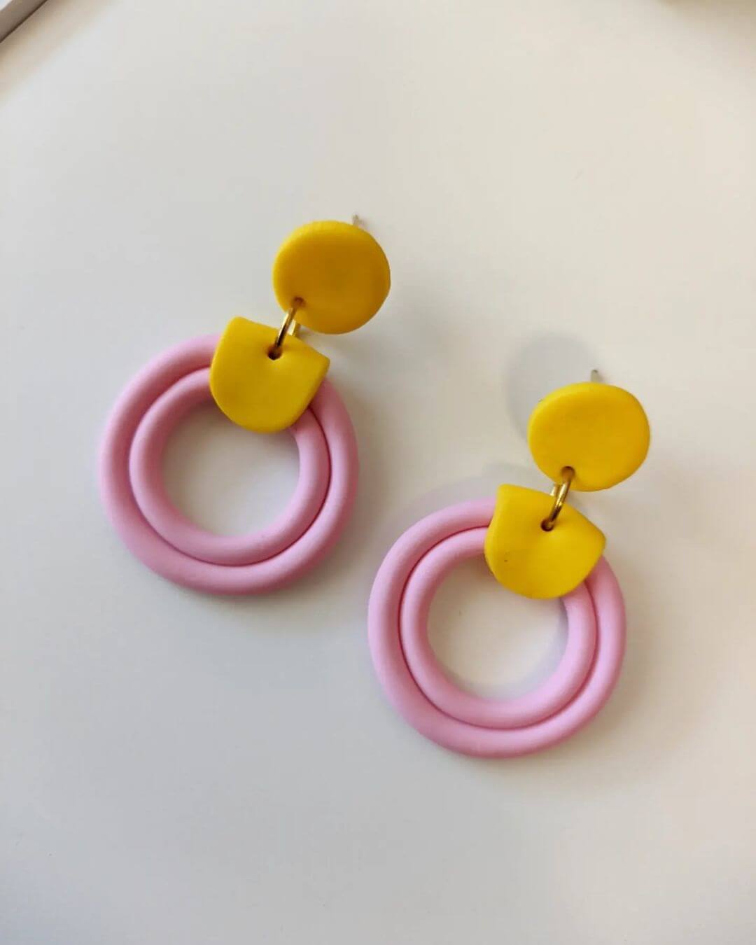 Pink hoop earrings with yellow accents made from polymer clay, made with tube style design.