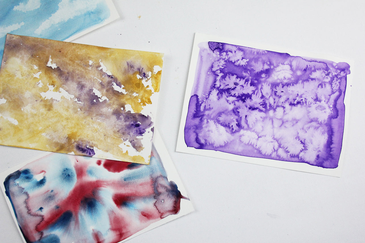 Three watercolour artworks laying on a white table.