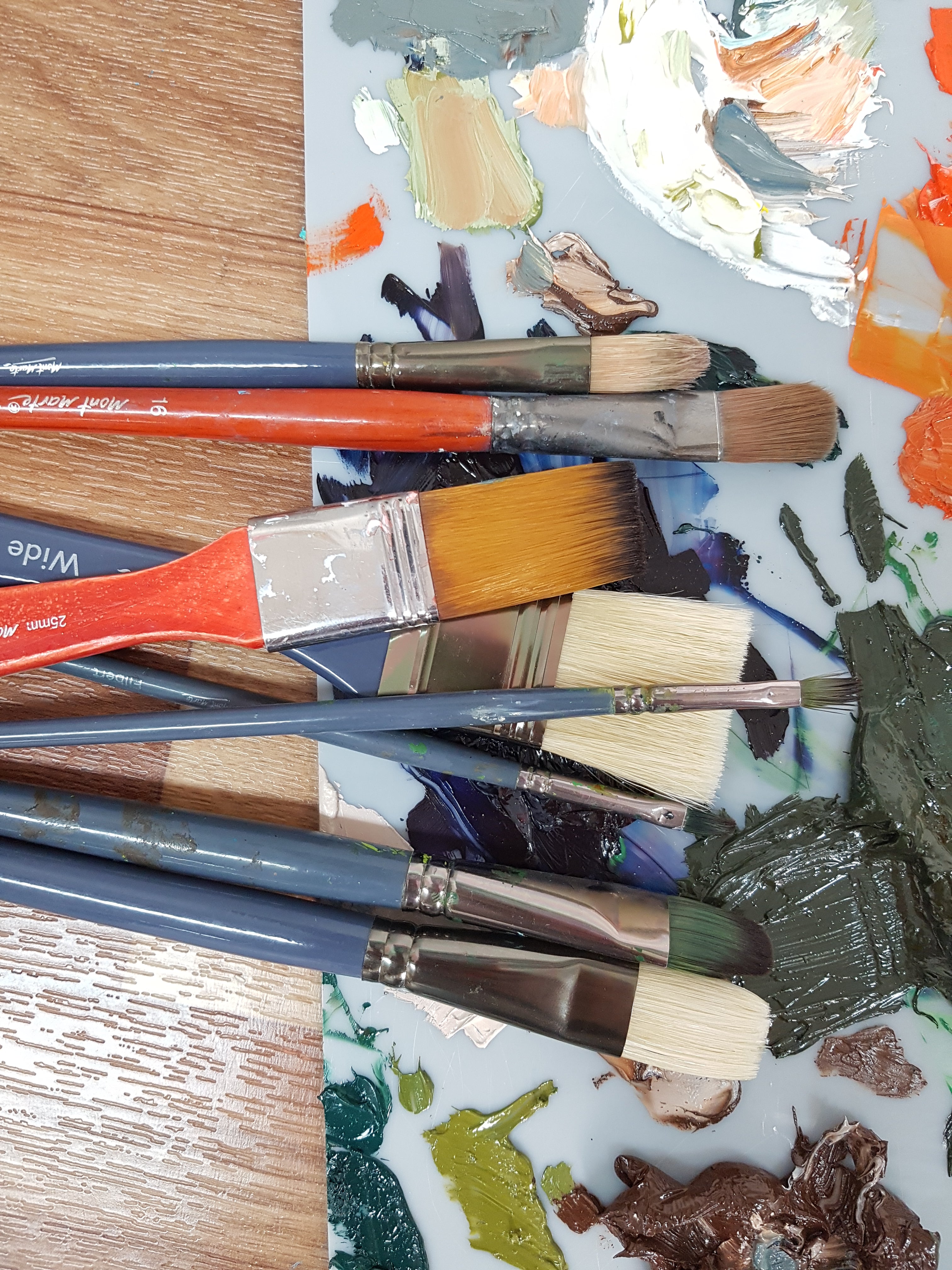 Various sized paint brushes on messy palette.
