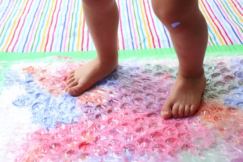 Child standing on painted bubble wrap.