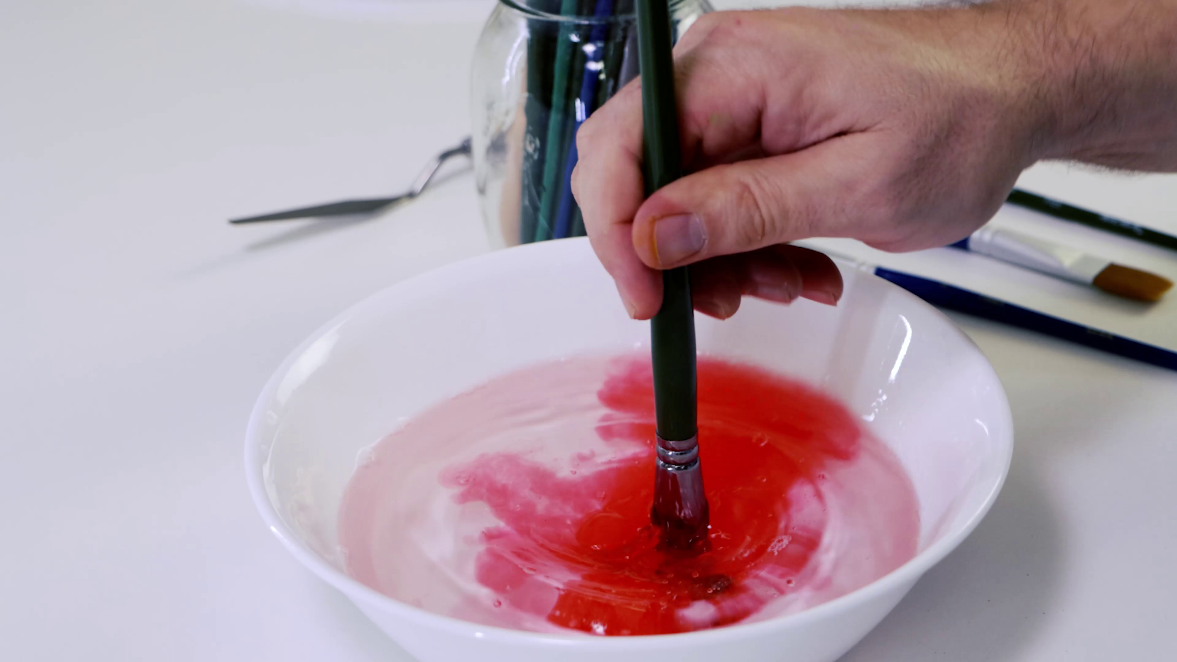 3. A paintbrush being dipped into water and releasing red paint