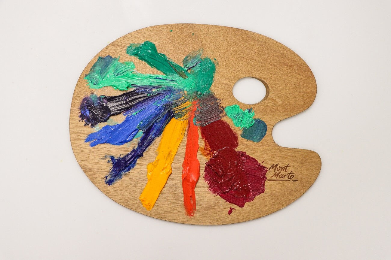 A wooden Mont Marte palette with a range of various oil paints squeezed onto it.