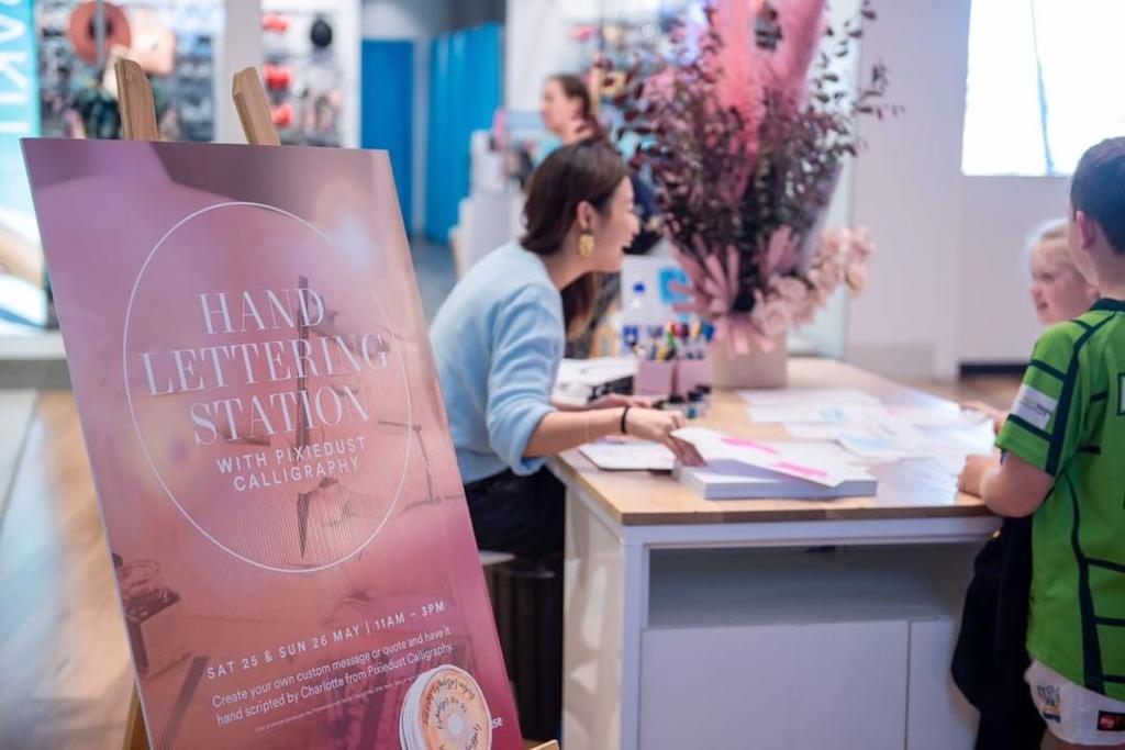 3. Charlotte at her hand lettering station, talking with customers