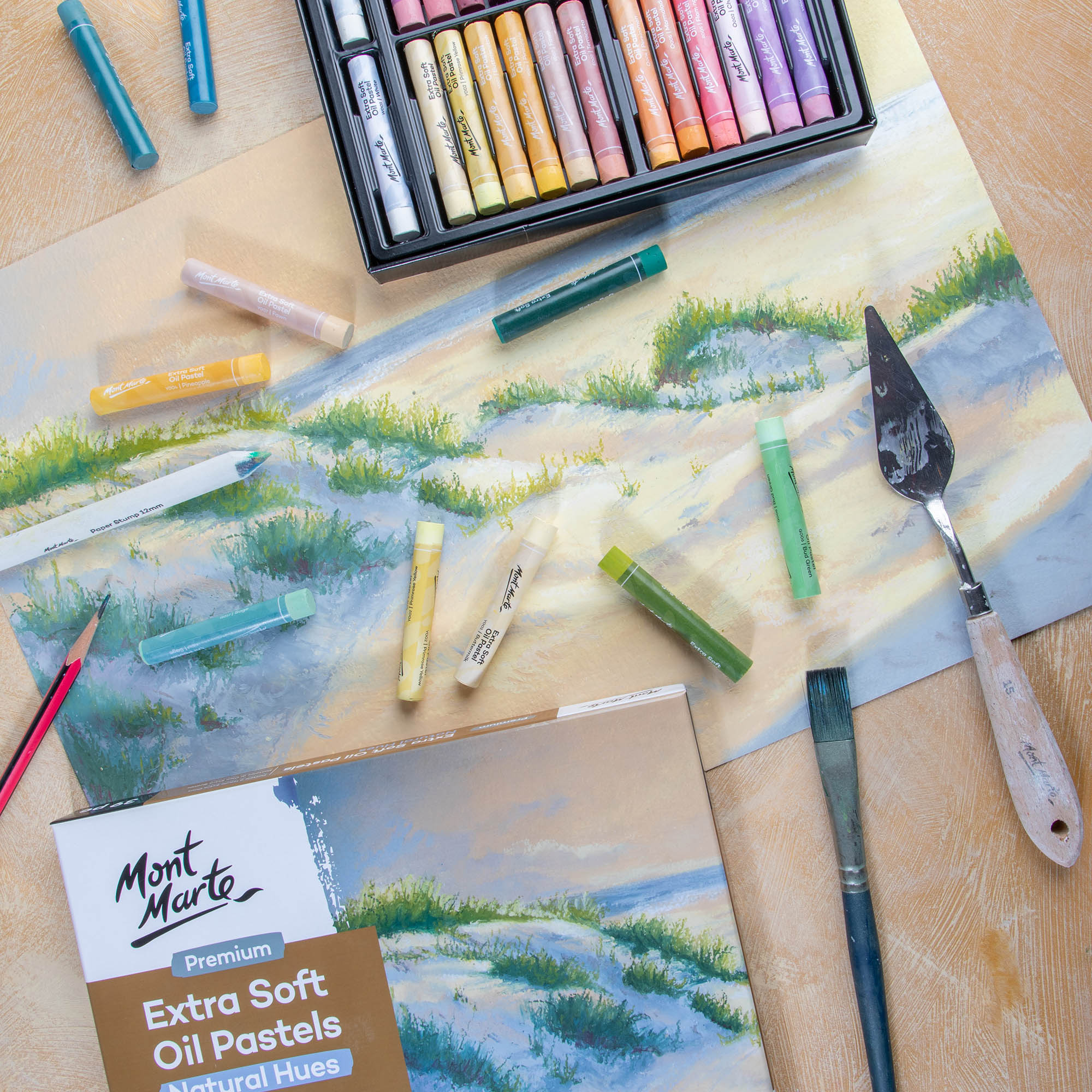 3. Extra Soft Oil Pastels Natural Hues scattered over a beach scene with a palette knife and brush in frame