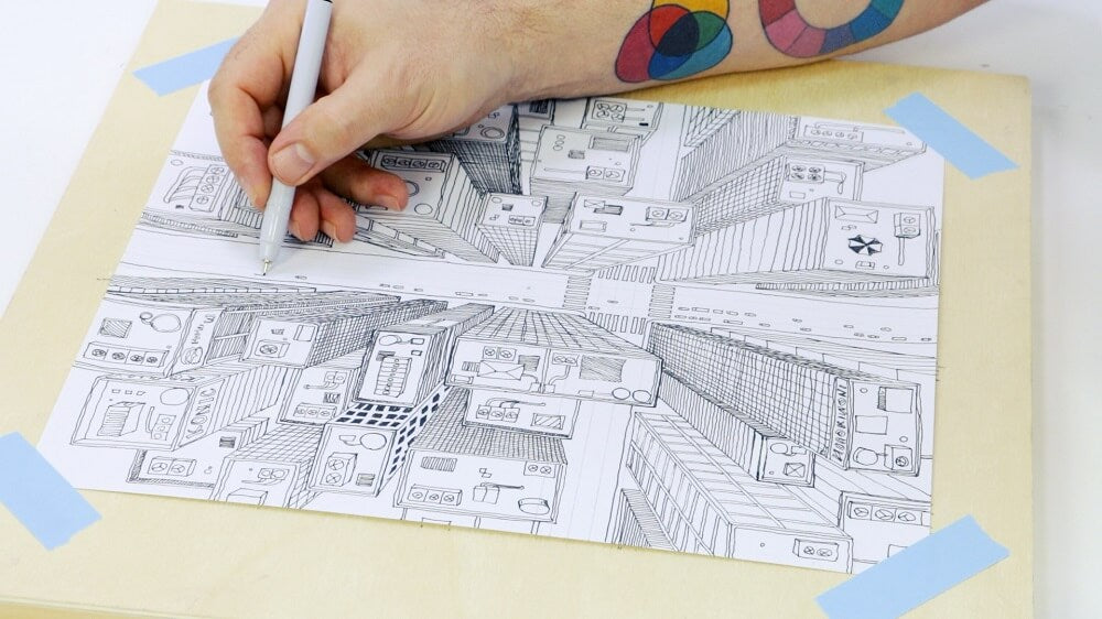 Hand holding a fine liner marker drawing an aerial cityscape.