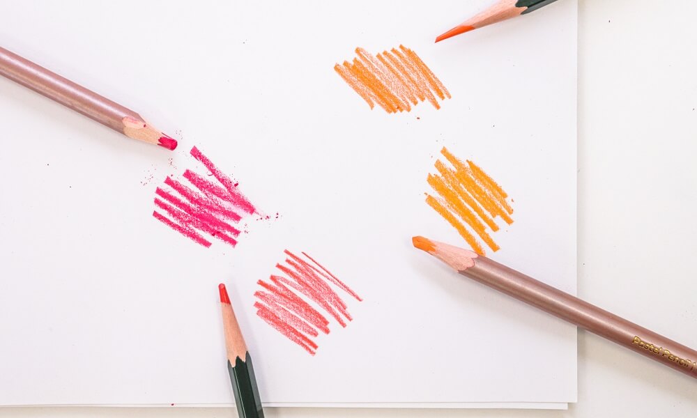 Pastel pencils laying next to coloured swatches with soft pastel swatches and soft pastels laying next to one another.