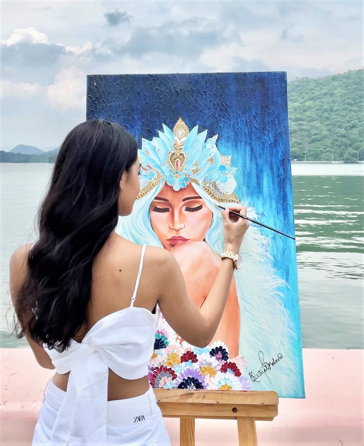 3. @Quinns_Arte painting a female portrait with an intricate headress by a body of water