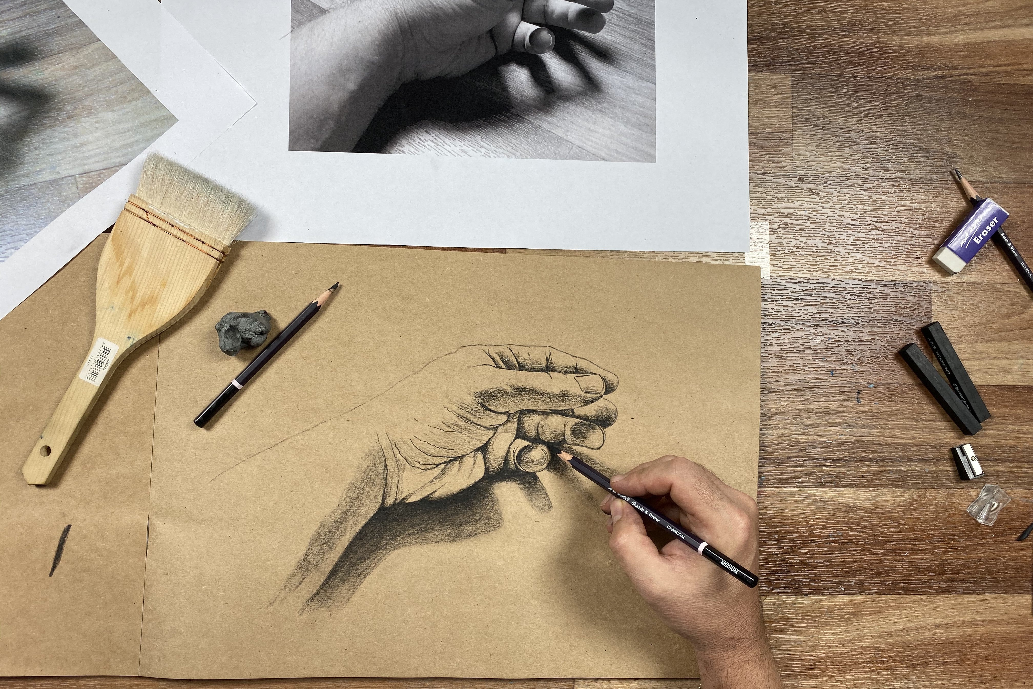 3. Sketch of a hand done in charcoal on tan toned paper