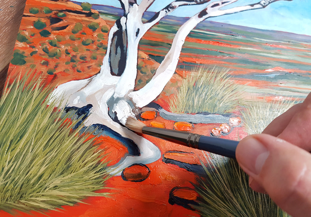 Brush painting white bark using white oil paint onto a tree in an Australian desert scene oil painting.