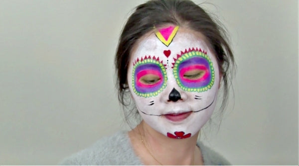 Woman wearing face paint for Halloween with a Mexican sugar skull design.