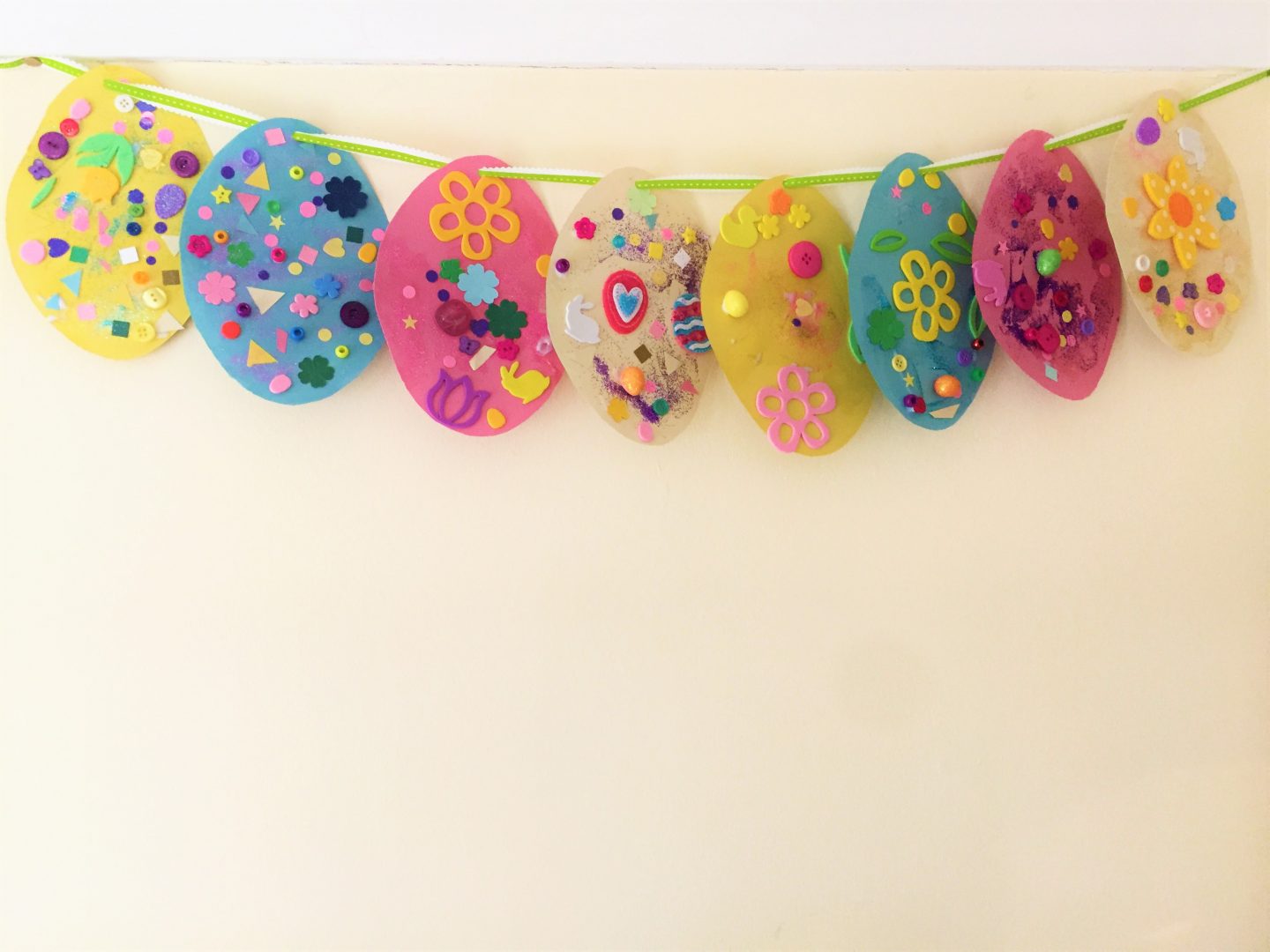 Easter egg collage bunting on a white wall.