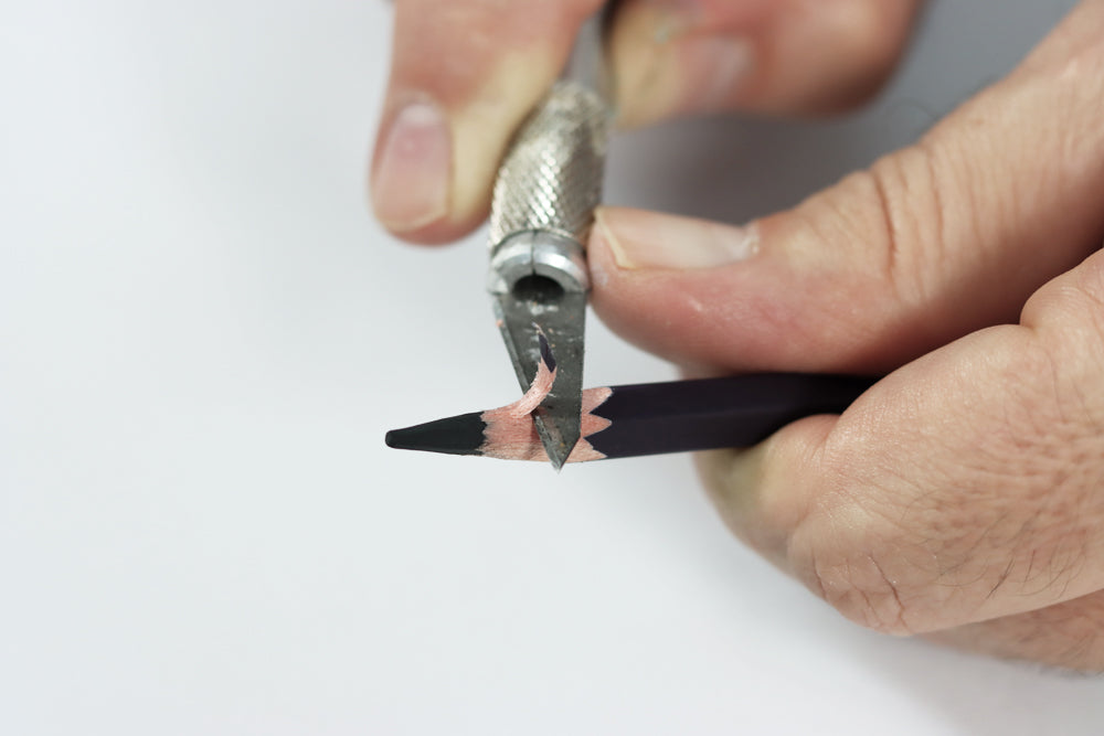 Sharpening a charcoal pencil with a hobby knife and placing it on the side