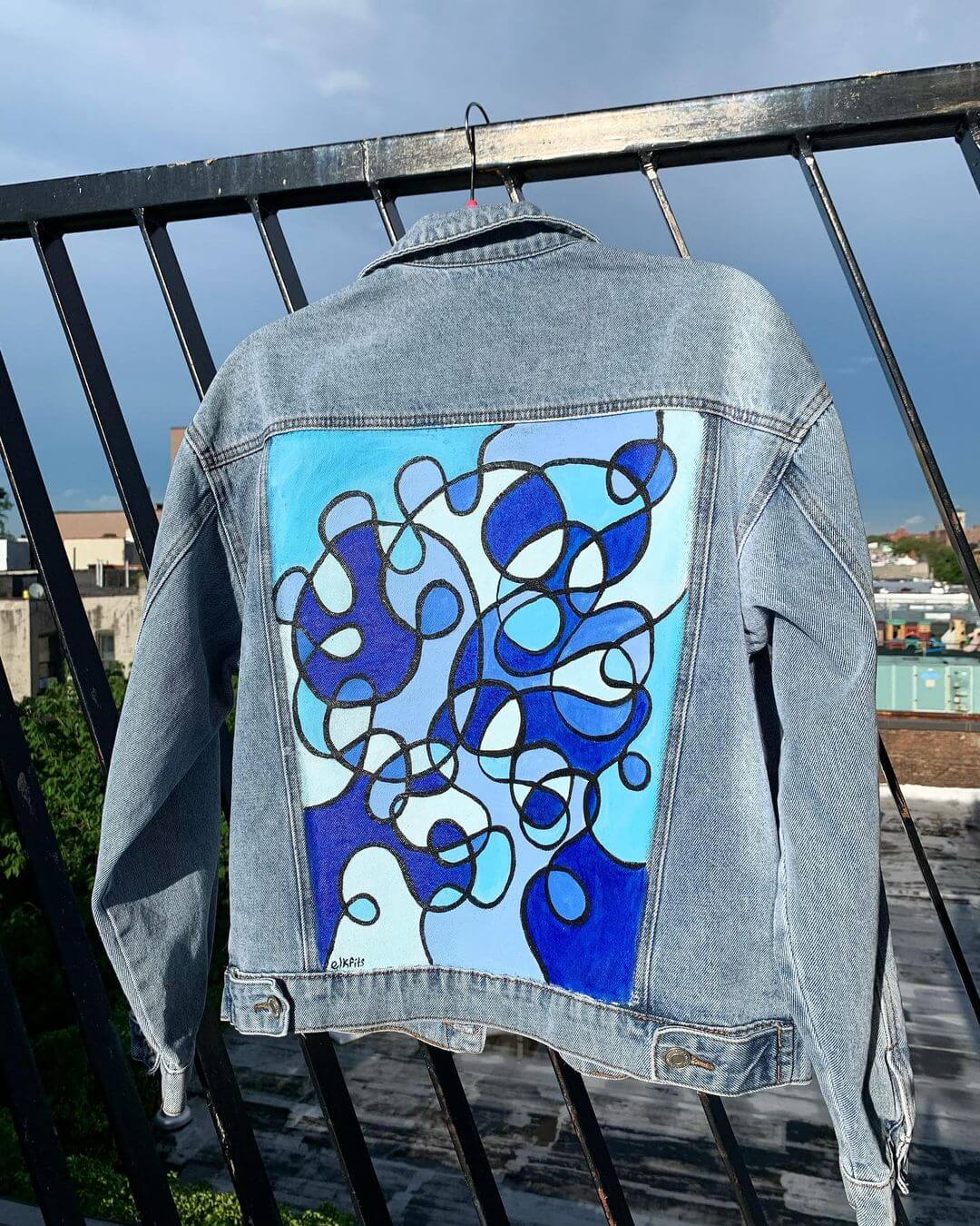 A blue denim jacket hanging on a fence.