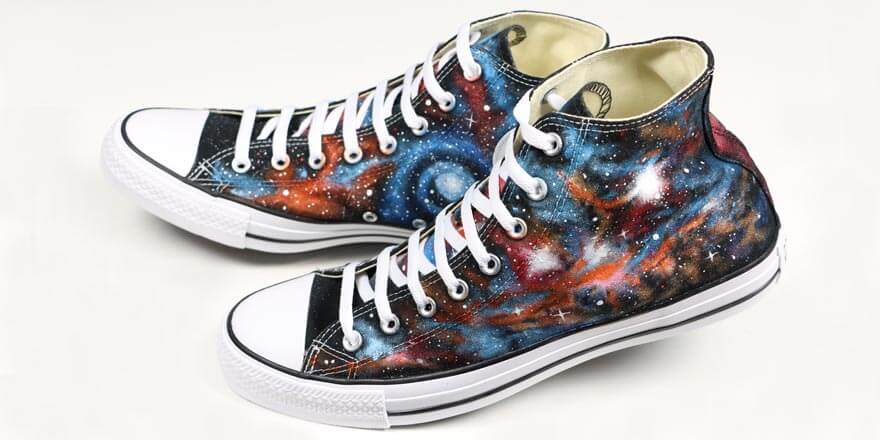 A pair of sneakers that have been painted with a space galaxy pattern.