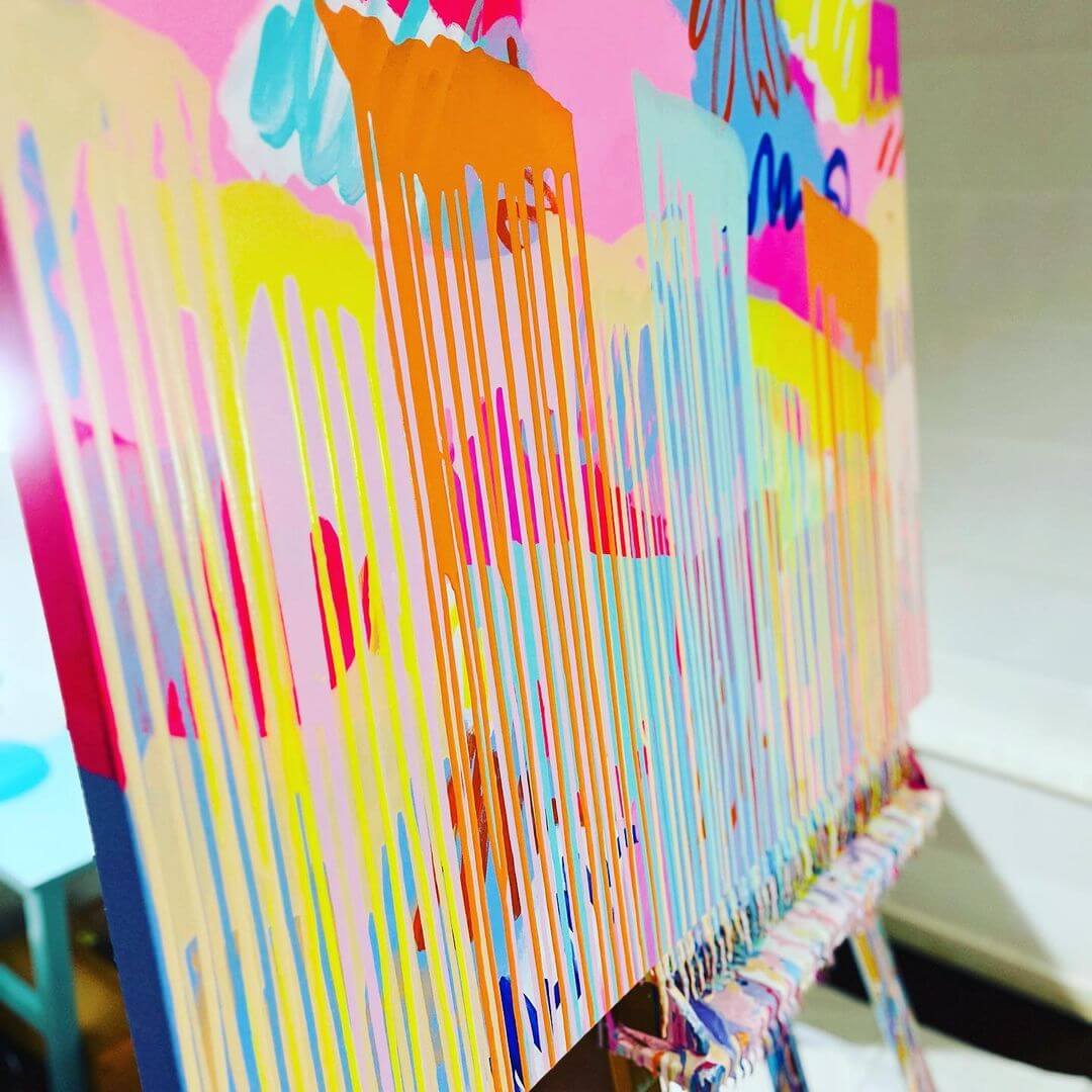 4. A side photo of a coloured canvas with various paint drips dripping down the wooden easel.