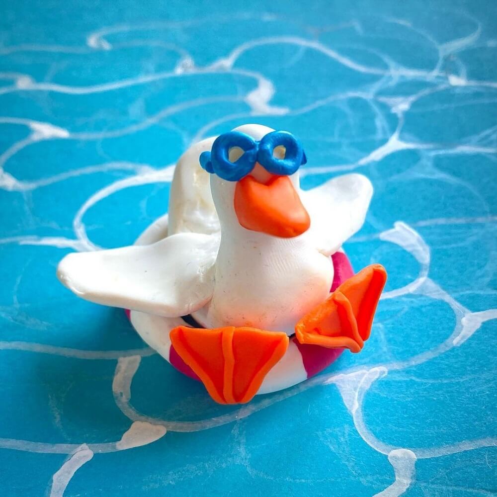 A white duck sitting in a life ring with blue glasses made from clay.