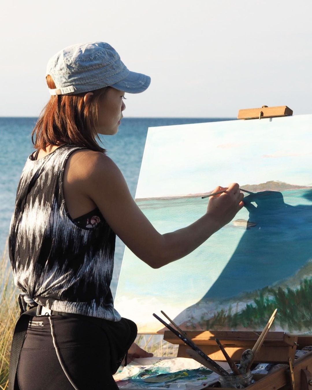 4. Candy painting a seascape on an easel by the ocean