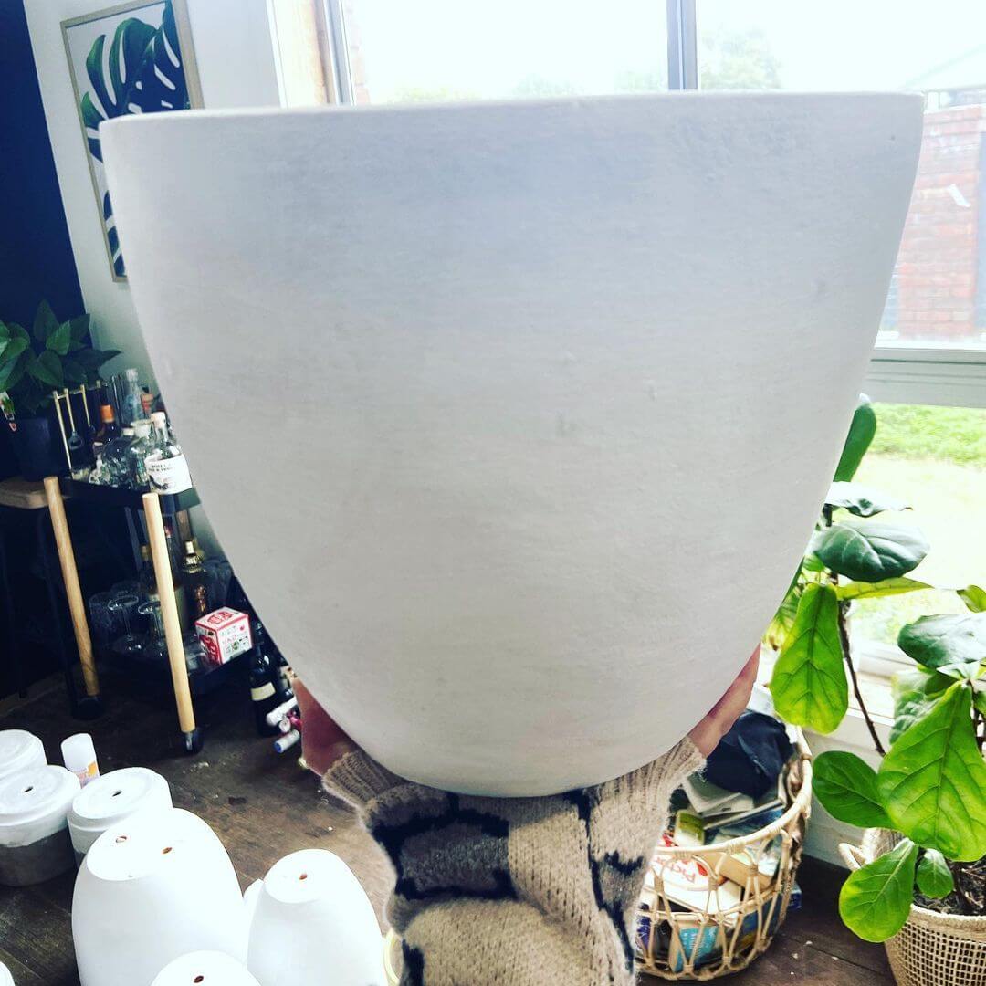 Cindy from Pot Dealer Geelong holding a white, primed pot in her studio to show  tips for painting terracotta pots.
