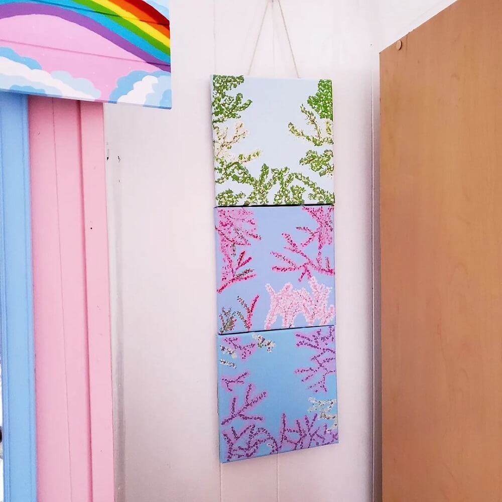 Three cherry blossom artworks hanging in a bright pink, coloured room.