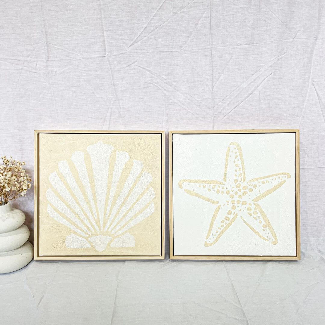 Two small artworks side-by-side painted in yellow with a sea shell on one and a starfish on the other.