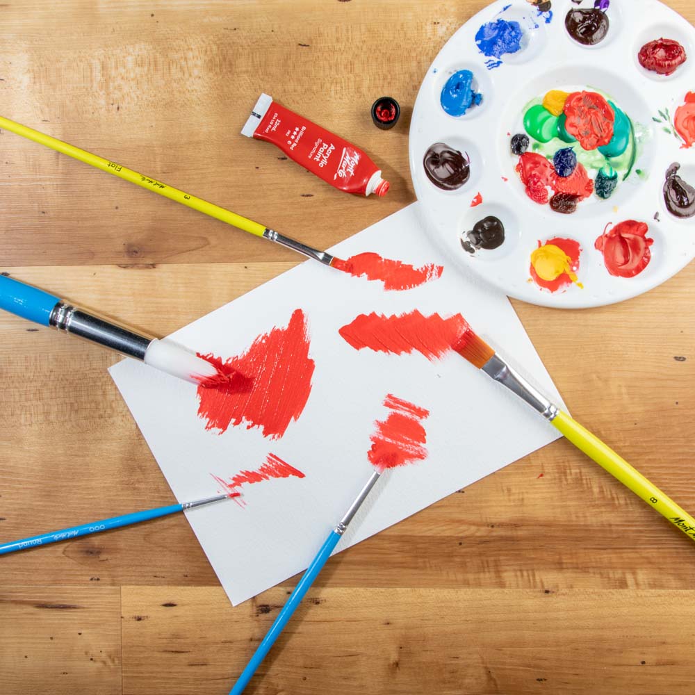 4. Various taklon paint brushes applying red paint to a piece of paper