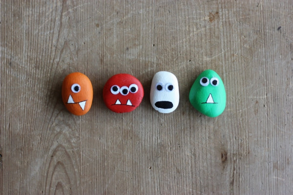 Four various rocks painted to look like monsters.