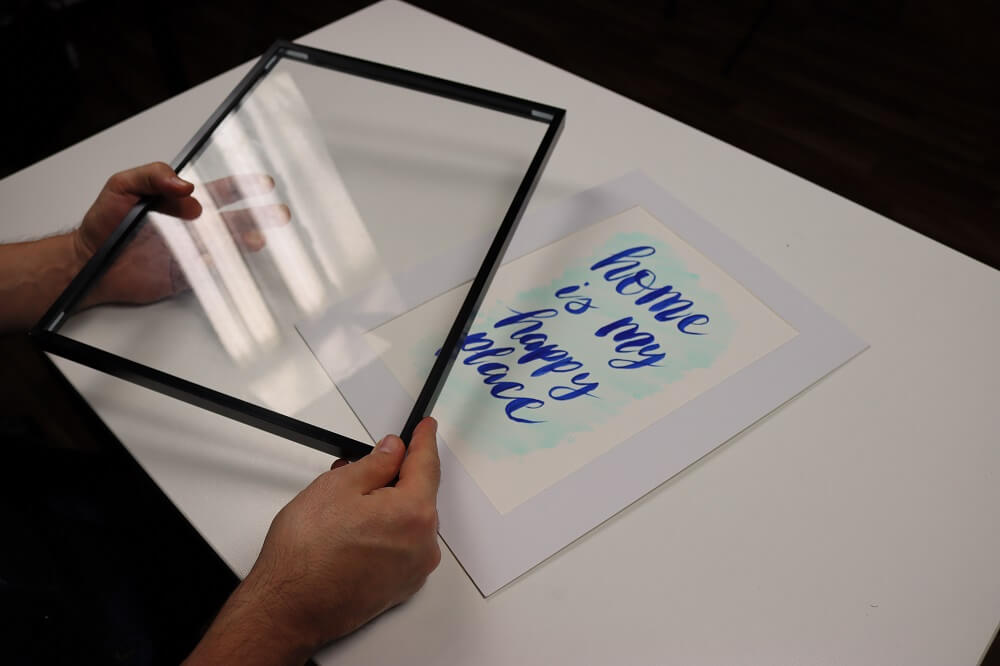 A hand holding a frame for hand lettering artworks.