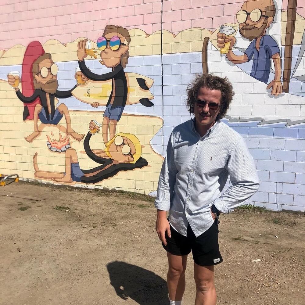 Ben Ross standing in front of a painted mural of Benny.