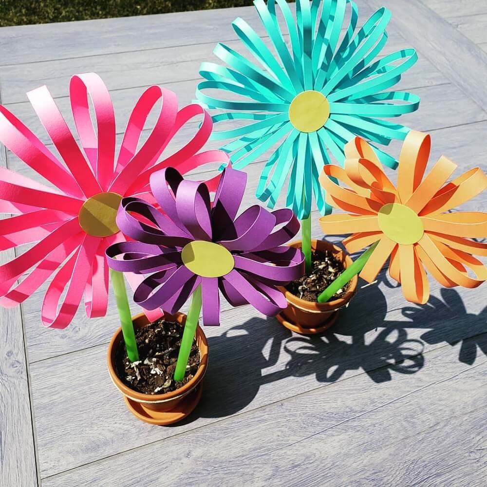 Four brightly coloured paper flowers made from strips of paper.