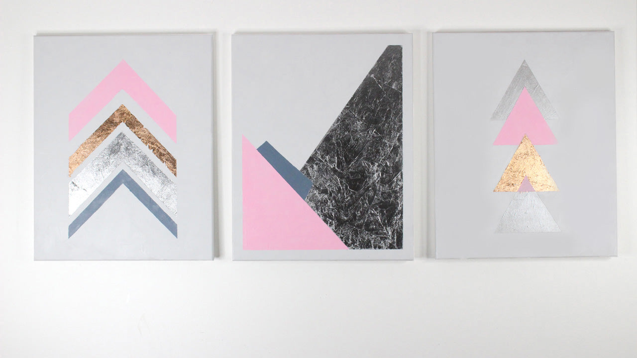 Three geometric artworks hanging on a white wall.