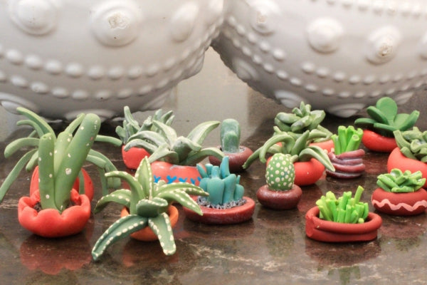 Polymer clay succulents sitting in clay pot plants.