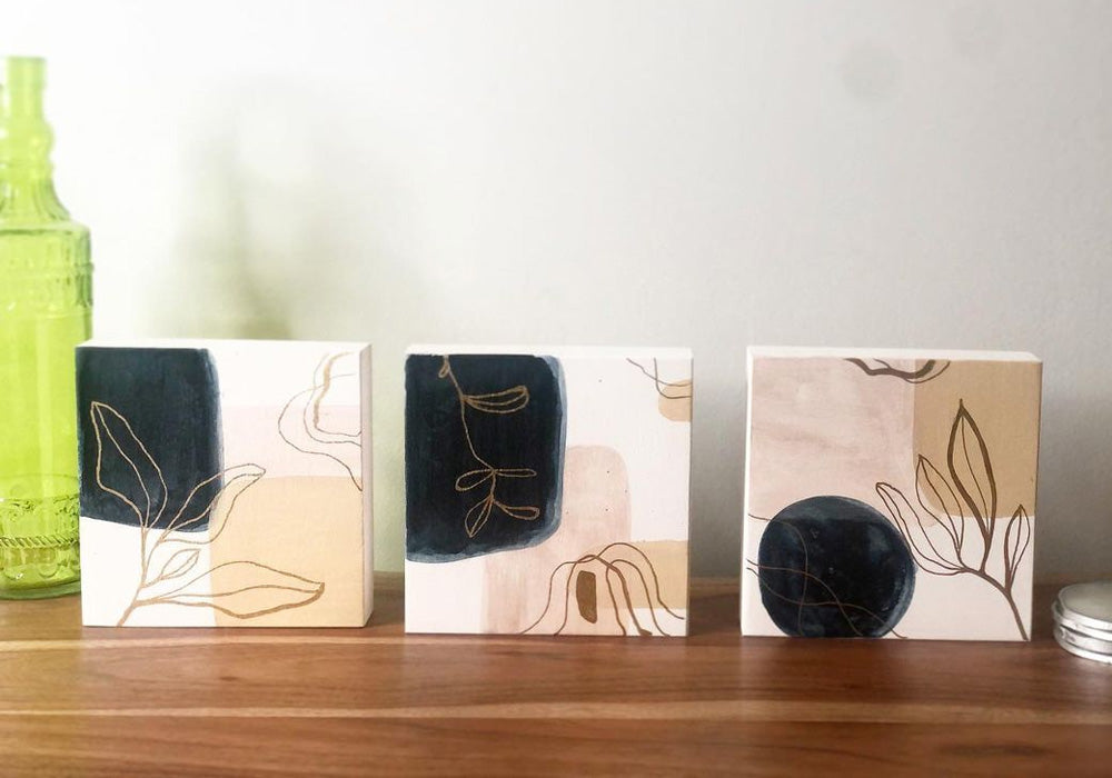 Three small canvases with plant line drawings on them.