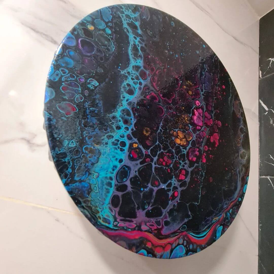 5. A black circular wooden board with blue and purple acrylic cells on it, sitting on a white marble bench.